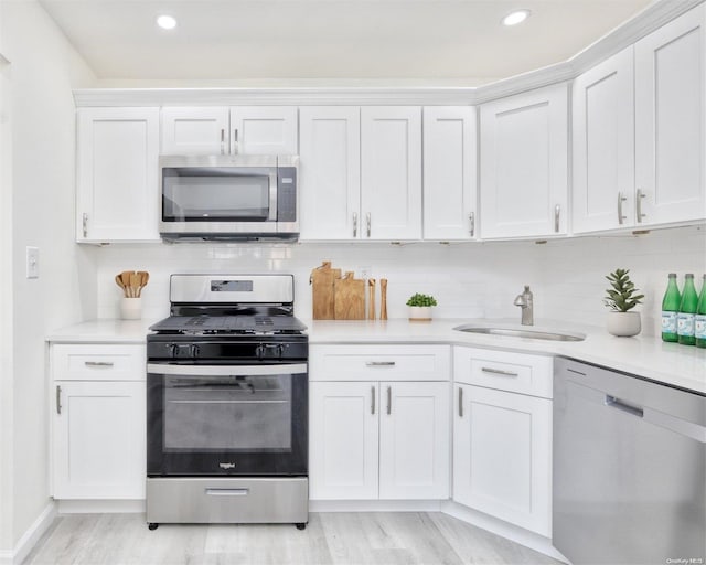 kitchen featuring white cabinets, light wood-type flooring, sink, and appliances with stainless steel finishes