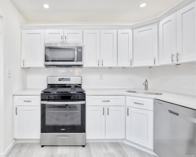 kitchen featuring sink, white cabinets, stainless steel appliances, and light hardwood / wood-style floors