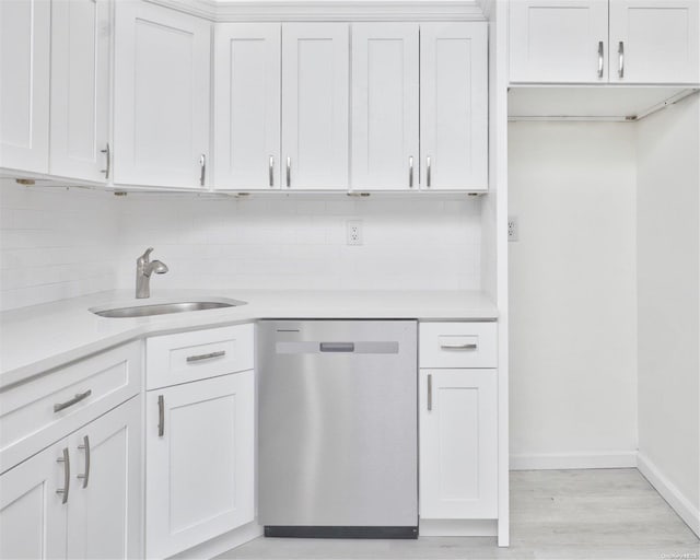 kitchen featuring decorative backsplash, stainless steel dishwasher, sink, light hardwood / wood-style flooring, and white cabinetry