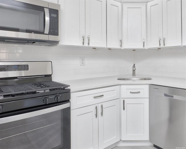 kitchen with decorative backsplash, stainless steel appliances, white cabinetry, and sink