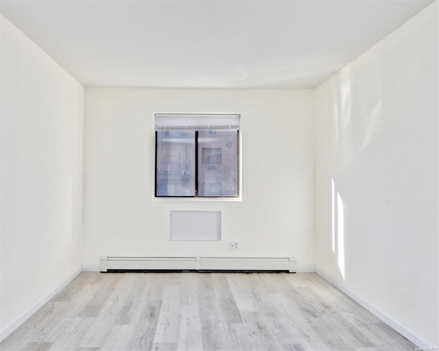 empty room with baseboard heating and light hardwood / wood-style flooring