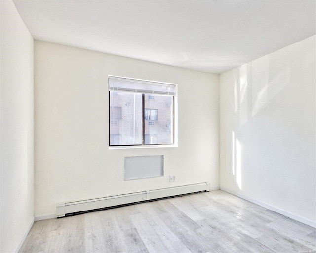 empty room with light wood-type flooring and a baseboard heating unit