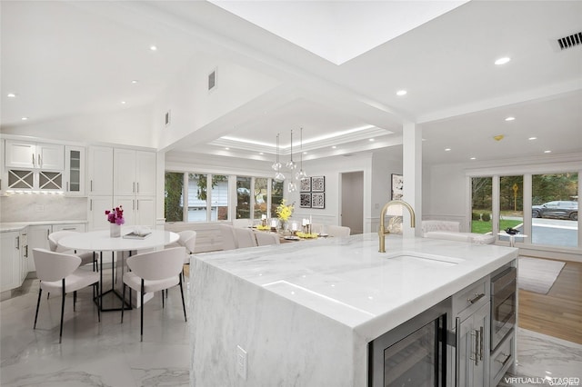 kitchen featuring wine cooler, a large island, sink, and white cabinets