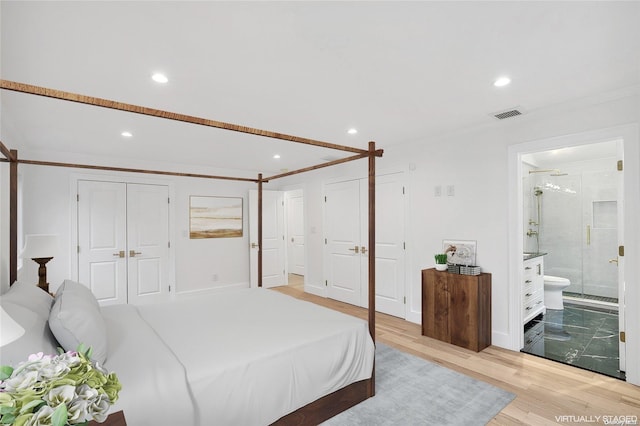 bedroom featuring a closet, light wood-type flooring, ornamental molding, and ensuite bath