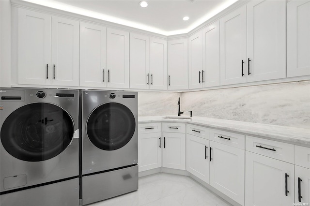 laundry area with washing machine and clothes dryer, sink, and cabinets