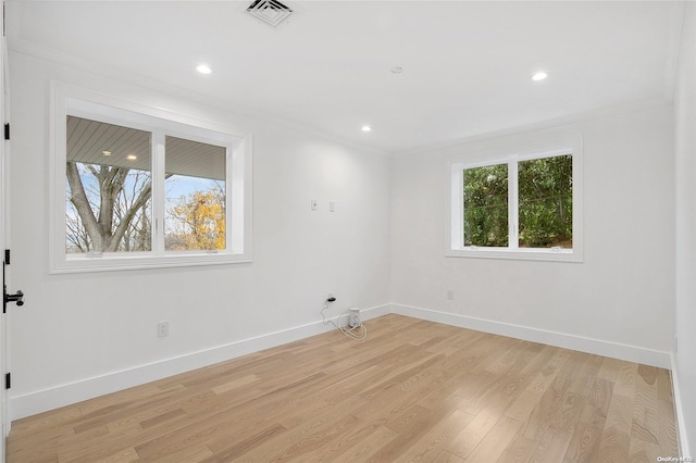 empty room featuring light hardwood / wood-style floors, crown molding, and a healthy amount of sunlight