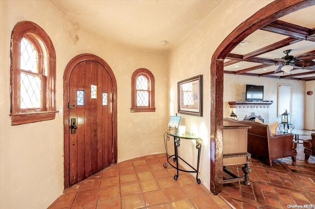 foyer entrance with ceiling fan, plenty of natural light, beamed ceiling, and coffered ceiling