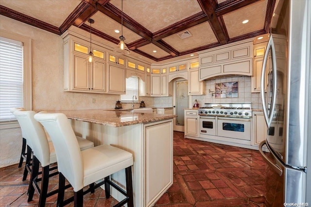 kitchen featuring stainless steel refrigerator, hanging light fixtures, coffered ceiling, double oven range, and cream cabinetry