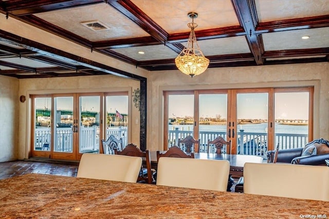 unfurnished dining area with a water view, plenty of natural light, and coffered ceiling