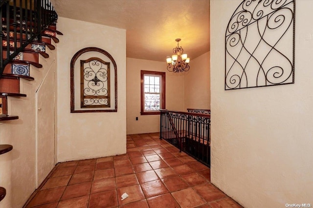 corridor featuring dark tile patterned flooring and a chandelier