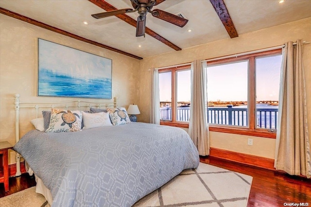 bedroom featuring hardwood / wood-style flooring, ceiling fan, beam ceiling, and a water view