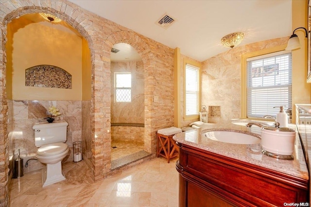 bathroom with walk in shower, vanity, toilet, and tile walls