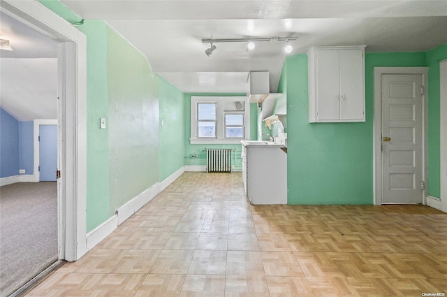 kitchen featuring white cabinetry, radiator heating unit, light parquet floors, and track lighting