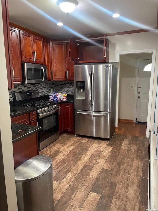 kitchen featuring dark stone countertops, decorative backsplash, dark hardwood / wood-style floors, and appliances with stainless steel finishes