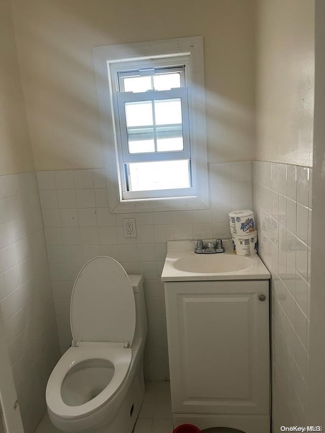 bathroom featuring toilet, vanity, tile patterned floors, and tile walls