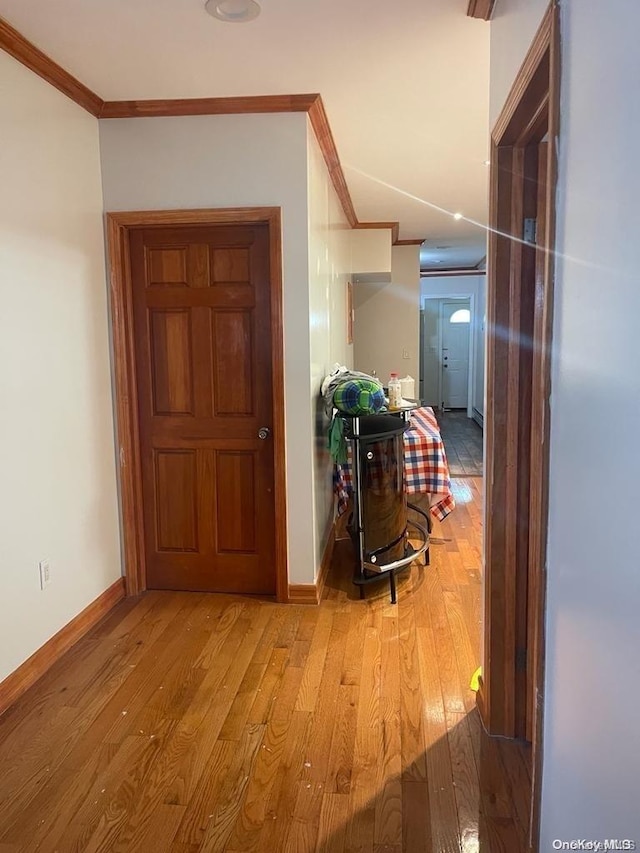 corridor with light hardwood / wood-style floors and ornamental molding