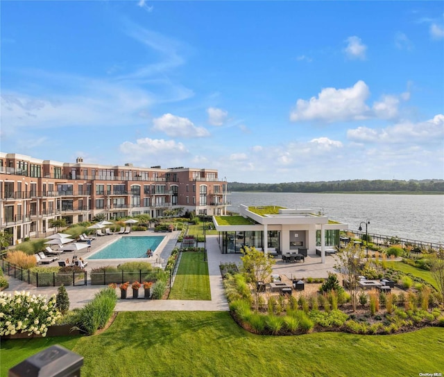 view of pool featuring a patio, a water view, and a lawn