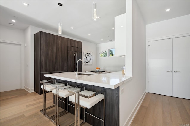 kitchen featuring pendant lighting, light hardwood / wood-style flooring, a breakfast bar area, and sink