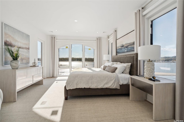 bedroom with light colored carpet and a water view