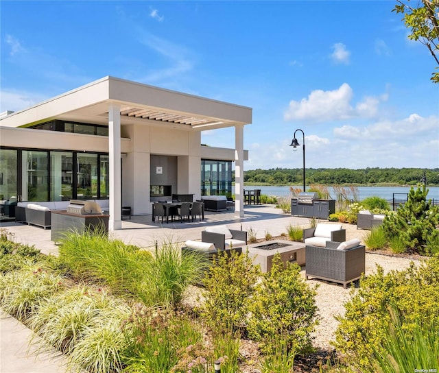 view of patio with a water view and an outdoor living space with a fire pit