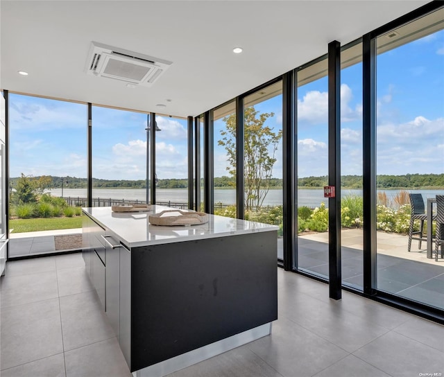 kitchen featuring floor to ceiling windows, a spacious island, light tile patterned flooring, and a water view