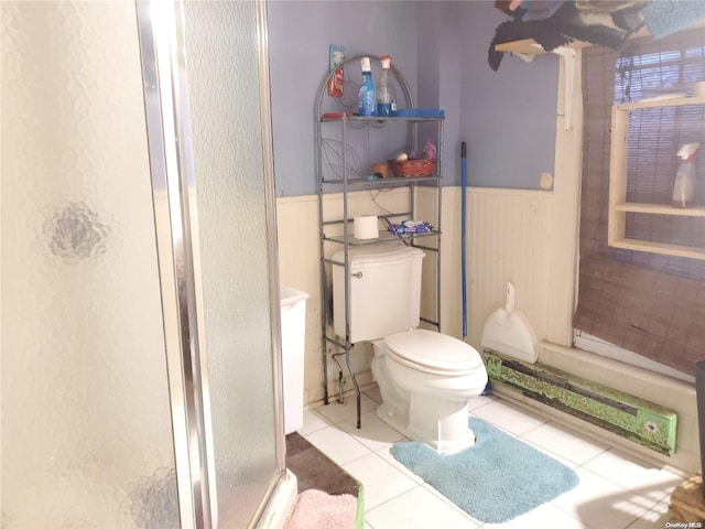 bathroom featuring tile patterned flooring, toilet, and a shower with shower door