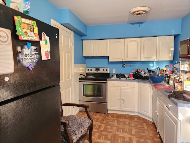 kitchen featuring electric range, white cabinetry, black fridge, and light parquet flooring