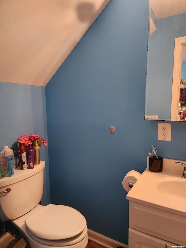 bathroom featuring vanity, lofted ceiling, and toilet