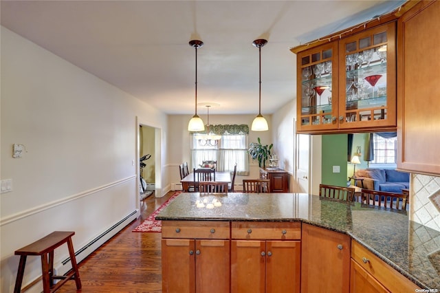 kitchen with decorative light fixtures, dark hardwood / wood-style flooring, dark stone counters, and a baseboard radiator