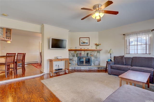 living room with a fireplace, crown molding, hardwood / wood-style floors, and ceiling fan