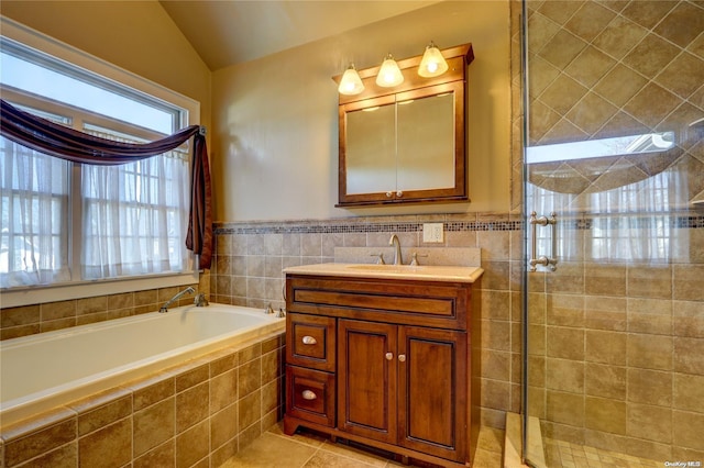 bathroom featuring vanity, lofted ceiling, a shower with door, tile patterned flooring, and tile walls