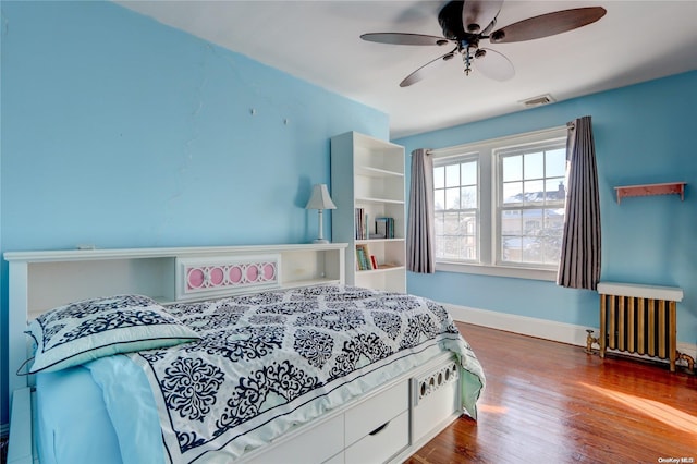 bedroom featuring hardwood / wood-style flooring, ceiling fan, and radiator heating unit