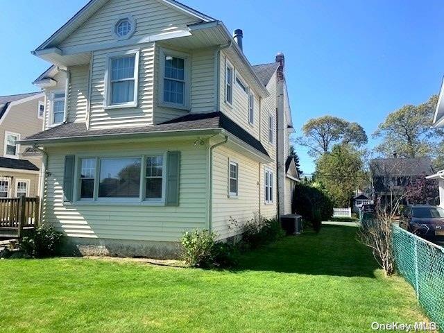 view of side of home featuring a lawn and central air condition unit