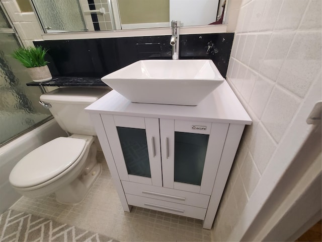 full bathroom featuring vanity, toilet, bath / shower combo with glass door, and tile patterned floors