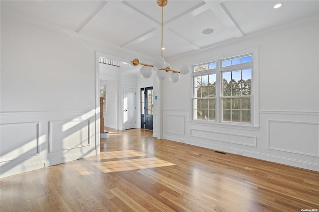 unfurnished dining area with hardwood / wood-style floors, ornamental molding, coffered ceiling, and a chandelier