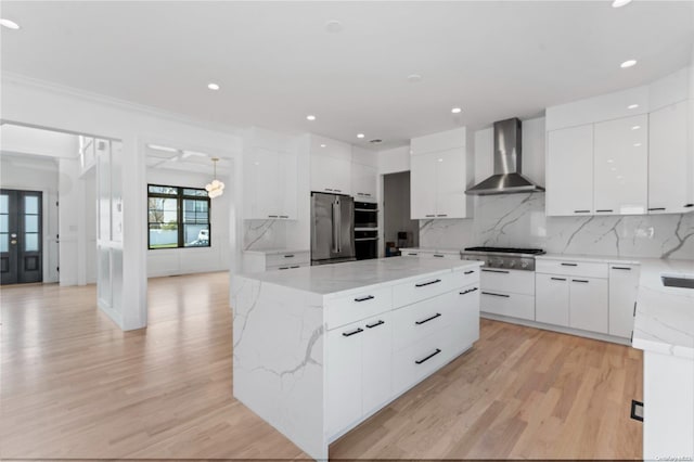 kitchen featuring white cabinetry, wall chimney exhaust hood, stainless steel appliances, and light wood-type flooring