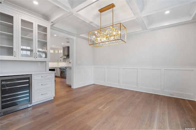 unfurnished dining area featuring beamed ceiling, light hardwood / wood-style flooring, wine cooler, and coffered ceiling