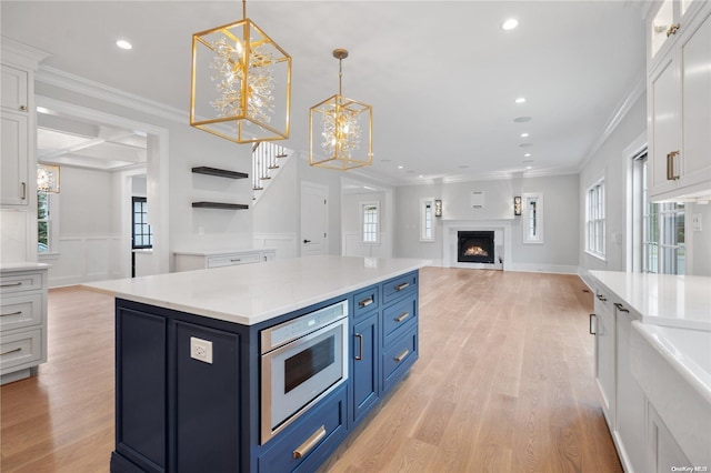 kitchen featuring blue cabinetry, a kitchen island, a notable chandelier, white cabinets, and light wood-type flooring