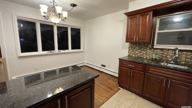 kitchen with pendant lighting, an inviting chandelier, dark stone counters, and sink