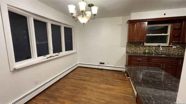 interior space with sink, a baseboard radiator, an inviting chandelier, dark hardwood / wood-style flooring, and decorative backsplash