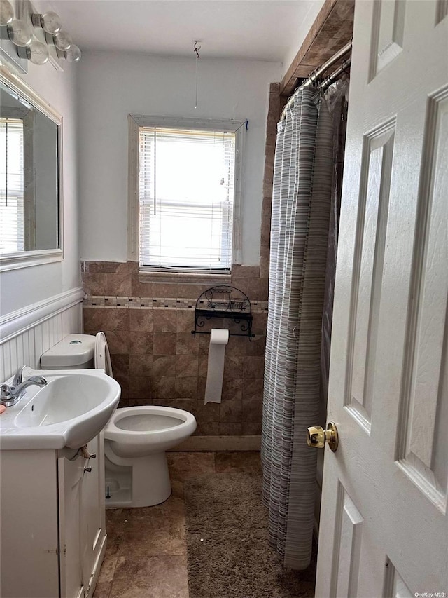 bathroom with plenty of natural light, vanity, tile walls, and toilet