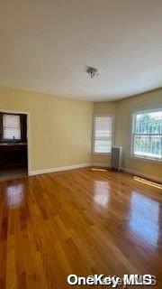 unfurnished room with hardwood / wood-style floors and radiator heating unit