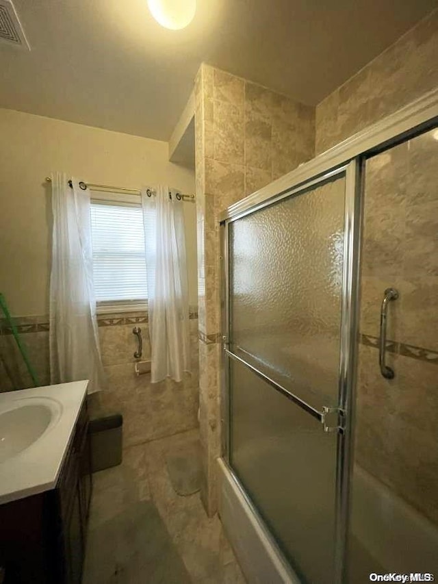 bathroom featuring shower / bath combination with glass door and vanity