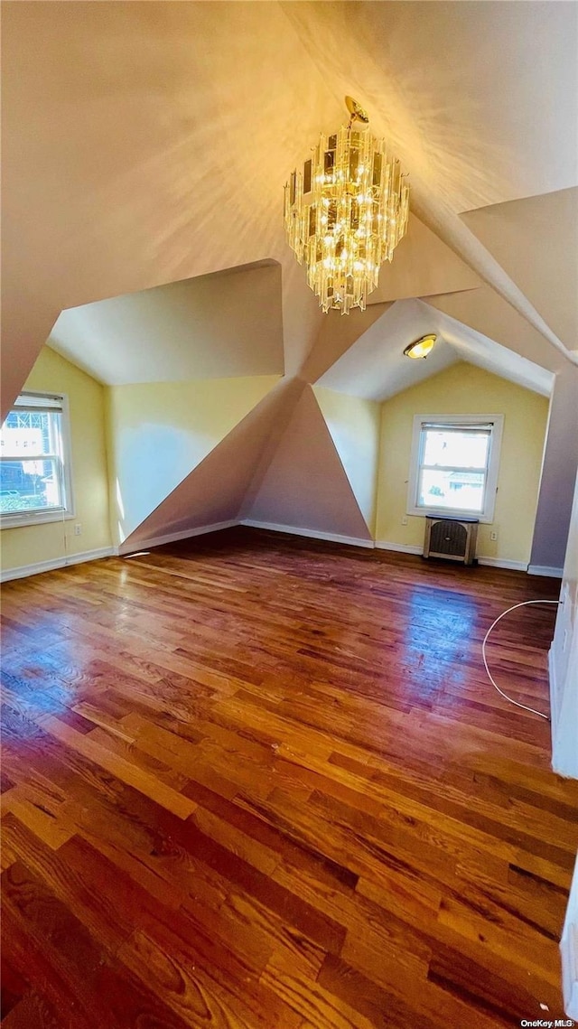 additional living space featuring dark hardwood / wood-style floors, a healthy amount of sunlight, and vaulted ceiling