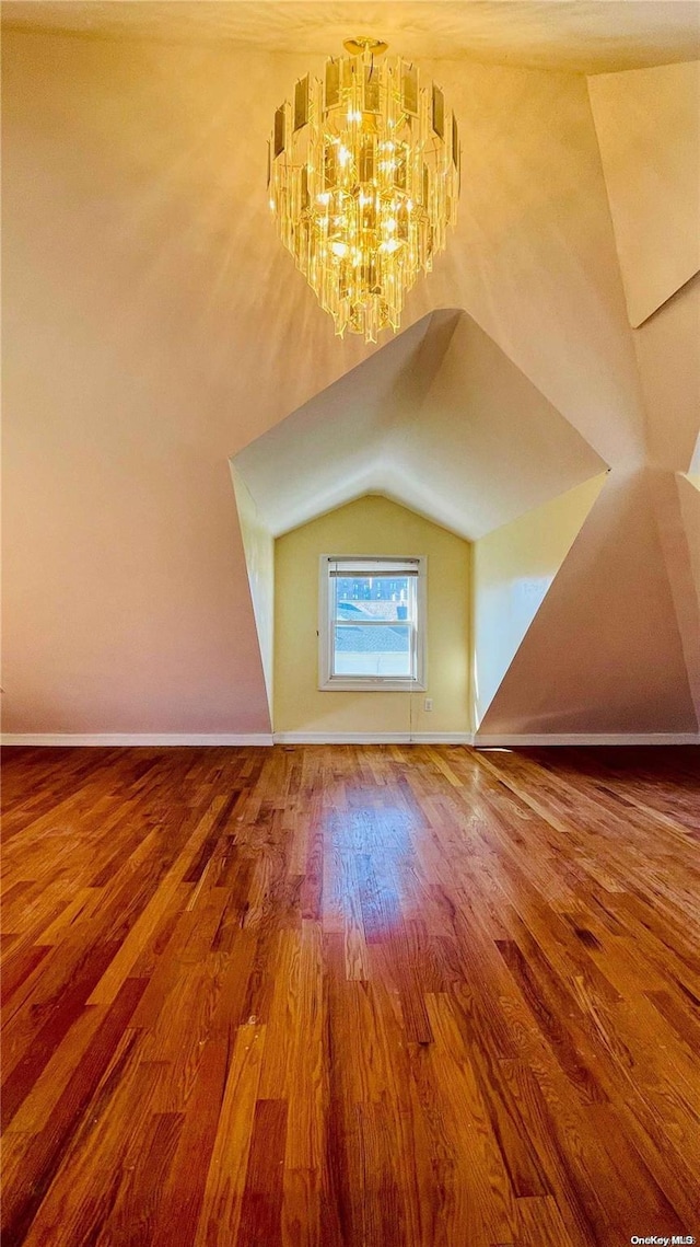 bonus room featuring hardwood / wood-style flooring, vaulted ceiling, and an inviting chandelier