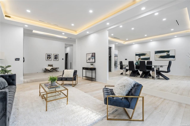 living room featuring a tray ceiling and light wood-type flooring