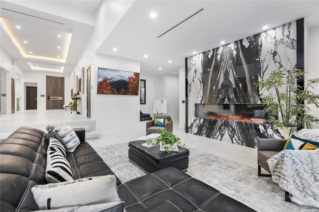 living room with a tray ceiling and a premium fireplace