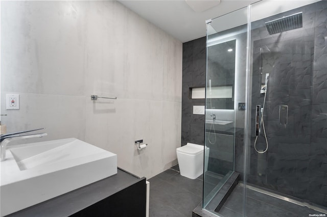 bathroom with tile patterned floors, toilet, a shower with door, vanity, and tile walls