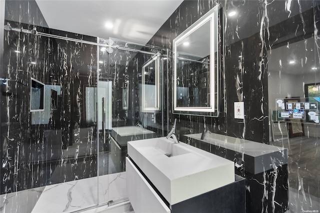 bathroom with vanity, a shower with door, and tile walls