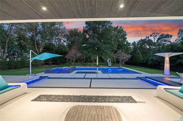 pool at dusk with a lawn and a patio area